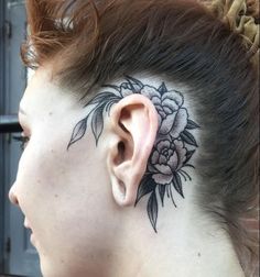 a woman with a flower tattoo on her side behind the ear is looking at something