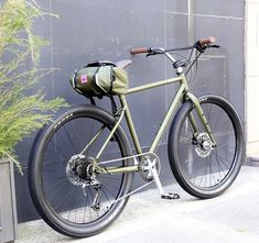 a green bike parked next to a building with a bag on the front wheel and back tire