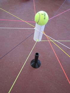 a tennis ball on top of a racket in the middle of a gym floor