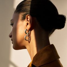 a woman with black hair and large earrings on her ear looking off into the distance