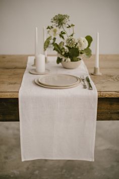 the table is set with white plates and silverware