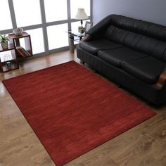 a living room with a black couch and red rug