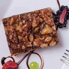 a piece of cake on a plate with some fruit and chocolate toppings next to it