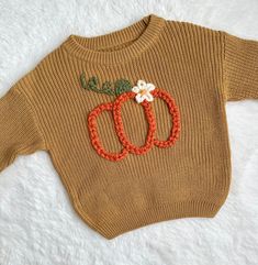 a knitted sweater with two pumpkins on the front and one flower on the back