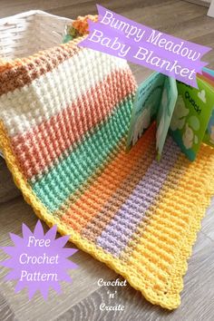 a crocheted baby blanket sitting on top of a wooden floor