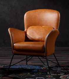 a brown leather chair sitting on top of a wooden floor next to a black wall