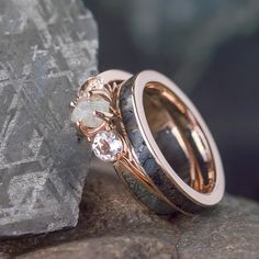 two wedding rings sitting on top of a rock next to some rocks and stone chips