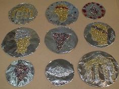 six pieces of tin foil with gold and silver designs on them are arranged in the shape of handprints