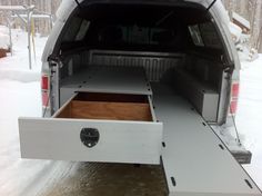 the back end of a white truck with its cargo compartment open in the snowy woods