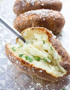 baked potatoes with parmesan cheese and herbs in them on a glass plate, ready to be eaten