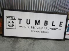 a sign that says tumble full service laundry is displayed in front of a metal wall