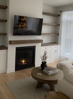 a living room filled with furniture and a flat screen tv mounted on the wall above a fire place