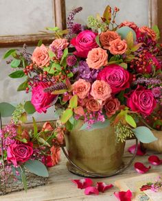 a vase filled with lots of pink and orange flowers on top of a wooden table