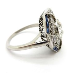 an antique style diamond and sapphire ring with two blue stones on the side, set in white gold