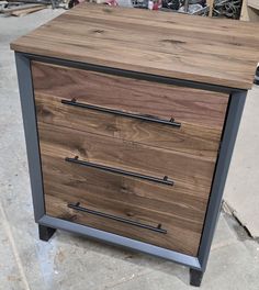 a wooden dresser sitting on top of a floor next to a pile of wood and metal