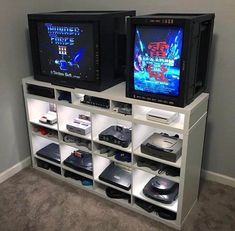 two televisions sitting next to each other on top of a white shelf filled with video games