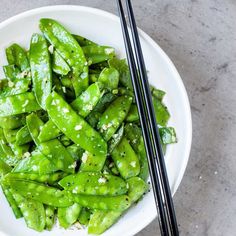 a white plate topped with green beans and chopsticks