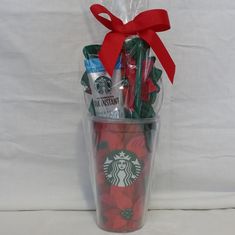 the starbucks cup is wrapped in plastic and has red flowers on it with a bow