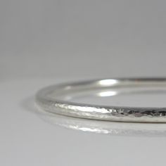 "This handmade heirloom quality sterling silver bangle is such a classic! Made from 3.2mm wide solid round sterling silver, it has such a pleasing weight. It is hand-formed and forged by me... the silver then gets hammered, hammered and hammered some more, creating a surface fully covered in tiny facets that provide a perfectly understated sparkle. The silver has been lovingly sanded and given a polished finish. Available in smooth (unhammered) finish as well, as can be seen in the last two pics Minimalist Hallmarked Sterling Silver Bracelet, Stackable Sterling Silver Bracelet For Anniversary, Sterling Silver Stackable Bangle For Anniversary, Handmade Round White Gold Bangle, Handmade Classic Round Sterling Silver Bracelet, Handmade Sterling Silver Bangle For Anniversary, Minimalist Sterling Silver Hallmarked Bracelet As Gift, Minimalist Engraved Round Bangle, Hammered Silver Round Bangle