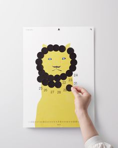 a person holding up a yellow and black poster with a lion on it's face