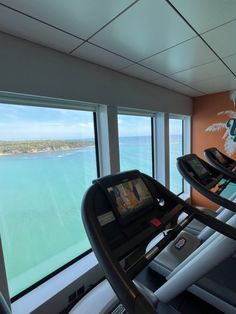 there are two treadmills in front of the large window overlooking the water and beach