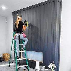 a woman on a ladder painting a wall