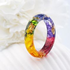 Introducing the 7 Chakra Rainbow Ring. Materials: yellow and orange marigold, green moss. geranium, cornflower, iris, purple immortelle, Gold24K Each chakra has its own color, all 7 colors are collected in the ring. Purple color develops wisdom and gives inspiration! Blue develops eloquence and intelligence! Green harmony and spiritual growth! Yellow develops will! Orange shapes feelings and emotions! Red color gives protection! Custom orders are welcome. Every item comes in a beautiful, individ Multicolor Flower Ring As Gift, Multicolor Flower Ring Gift, Multicolor Flower-shaped Wedding Rings, Handmade Multicolor Flower Rings, Colorful Handmade Ring Gift, Colorful Handmade Rings As Gift, Colorful Handmade Rings For Gifts, Multicolor Flower Ring As A Gift, Multicolor Flower Ring For Gift