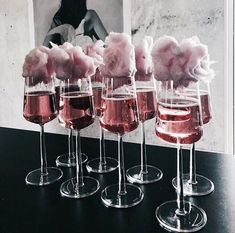 five wine glasses filled with pink liquid and cotton floss in front of a photo