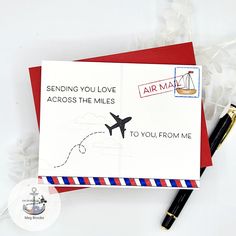 an air mail envelope with a stamp on it and a pen sitting next to it