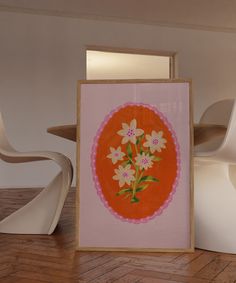 an orange and pink painting with white flowers in the center on a wooden floor next to a chair