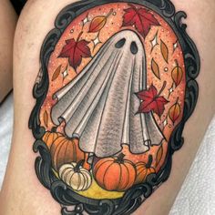 a woman's thigh with a ghost and pumpkins in the frame on it