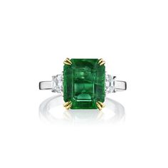 This 3 stone, 4.99ct natural green emerald ring. Flanked by Cadillac-cut diamonds weighing 0.49 carats. Has 18KT yellow gold prongs and diamonds are set in 18kt white gold and a polished 18kt white gold band. The ring total weight is 5.48 carats. Green Three-stone Emerald-cut Emerald Ring, Three-stone Emerald Cut Green Emerald Ring, Green Three Stone Emerald Cut Emerald Ring, Green Emerald Cut Three Stone Emerald Ring, Green Emerald Three Stone Diamond Ring, Asscher Cut Emerald Ring With Diamond Accents, Luxury Three Stone Diamond Emerald Ring, Luxury Three Stone Emerald Ring, Green Emerald Ring With Three Stone Baguette Cut