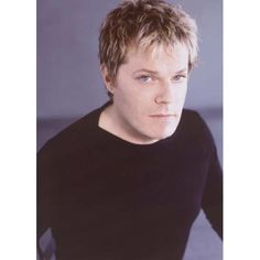 a close up of a person wearing a black shirt and looking at the camera with a serious look on his face