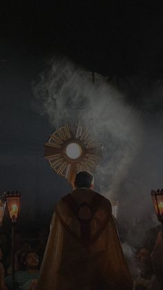 a man in a priest's robes standing next to two torches