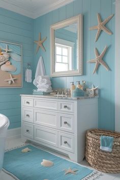 a bathroom with blue walls and white cabinets, starfish decor on the wall and rug