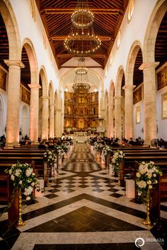 the inside of a church with chandeliers and flowers in vases on the pews