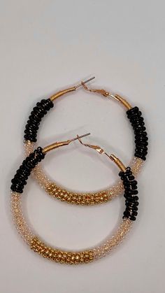 Embrace your bohemian spirit with our handcrafted Black & Gold Wire Wrapped Hoop Earrings. These one-of-a-kind earrings feature a mesmerizing swirl of black and gold seed beads meticulously wrapped around lightweight gold-tone hoops. Each bead is carefully secured by hand, creating a unique and textured design that catches the light and adds a touch of boho chic to any outfit.  The combination of black and gold exudes an air of sophistication, making these earrings perfect for both everyday wear and special occasions. Why You'll Love These Hoop Earrings: Handcrafted Artistry: Each pair is meticulously crafted with love and attention to detail. Unique Design: The wire-wrapped seed bead pattern ensures no two pairs are exactly alike. Bohemian Flair: Embrace a free-spirited aesthetic with the Adjustable Dangling Beads Hoop Earrings For Party, Adjustable Hoop Earrings With Dangling Beads For Party, Adjustable Hoop Beaded Earrings For Party, Wire Wrapped Beaded Hoop Earrings, Bohemian Small Hoop Beaded Earrings For Party, Bohemian Beaded Hoop Earrings For Party, Bohemian Small Hoop Earrings For Parties, Bohemian Hoop Beaded Earrings For Party, Bohemian Round Hoop Earrings For Party