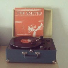 a record player sitting on top of a suitcase next to an orange sheet music album