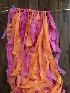 some orange and pink streamers hanging from a wooden wall