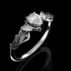 a white gold ring with three pears and leaves on the side, set against a black background