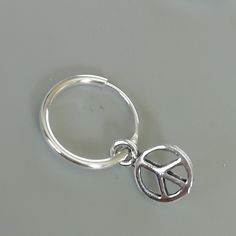 A PAIR of sterling silver hoops. Comes with a detachable tiny peace sign charm. The charm is multipurpose and can be used with a neck or bracelet chain too. Dimension: Hoop- mm Charm- mm Drop length- mm Price listed is for a PAIR of hoops. These earrings are made of 925 hypoallergenic sterling silver and comes with a 925 stamp. Can be packaged in a gift box. I can include a personal message from you if needed You are welcome to contact me at... bhavnakwintra1956@gmail.com For more beautiful piec Nickel-free Silver Huggie Septum Ring, Nickel Free Silver Metal Nose Rings, Nickel-free Silver Metal Nose Ring, Adjustable Nickel-free Round Huggie Earrings, Silver Pierced Huggie Septum Ring, Nickel-free Sterling Silver Septum Ring, Nickel Free Adjustable Huggie Earrings, Nickel-free Small Hoop Cartilage Earrings, Silver Metal Septum Ring As Gift