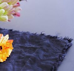 some flowers are sitting in a vase on a black piece of cloth with frayed edges