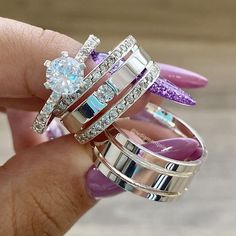 a person holding three different rings in their hand with purple nail polish on the nails