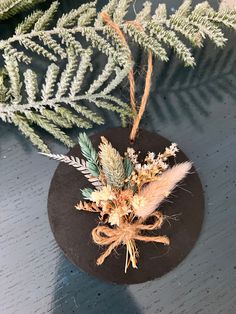 an ornament with feathers and flowers on top of a wooden table next to a plant