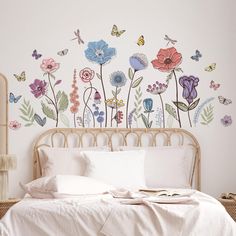 a bed sitting under a wall with flowers on it