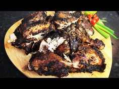 grilled chicken wings on a wooden plate with green beans and tomatoes in the background