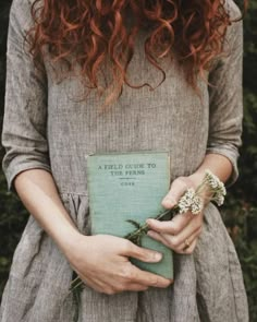 a woman holding a book with flowers in her hands