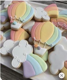 decorated cookies on a plate with rainbows and hot air balloons