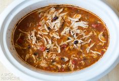 a white bowl filled with chicken tortilla soup on top of a wooden table