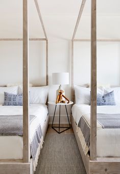 two beds in a bedroom with white walls and wooden posts on the headboard,